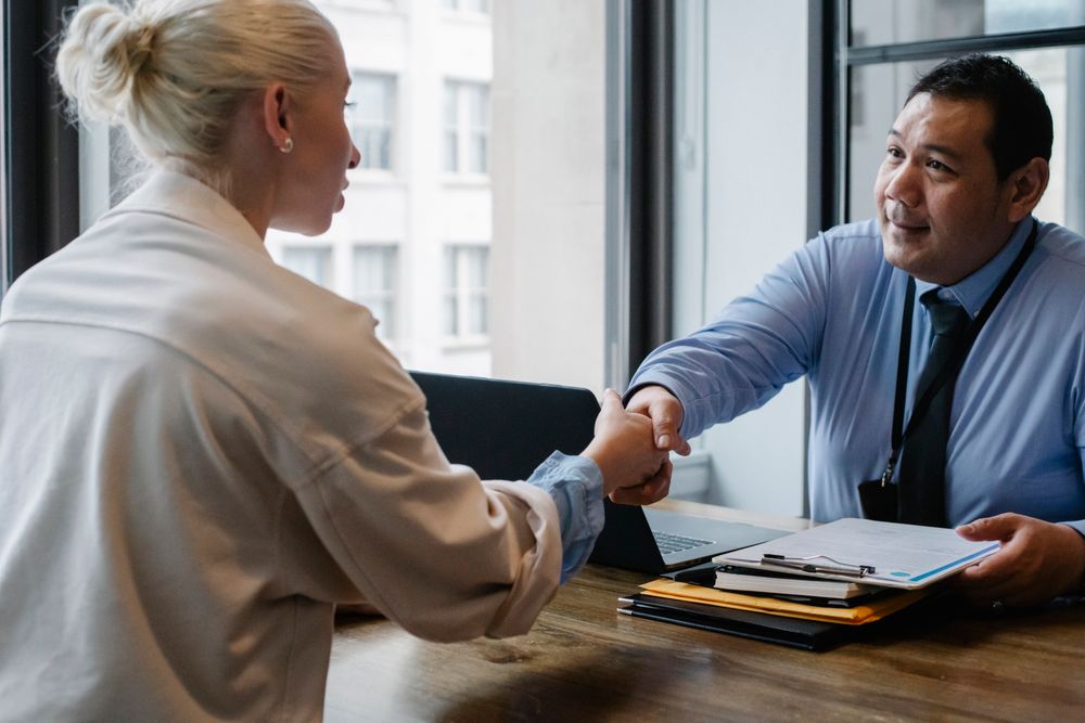 An insurance agent shaking hands with a client across a desk