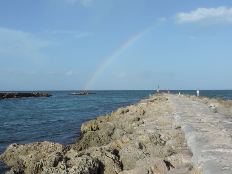 Rainbow over a rocky jetty and the ocean