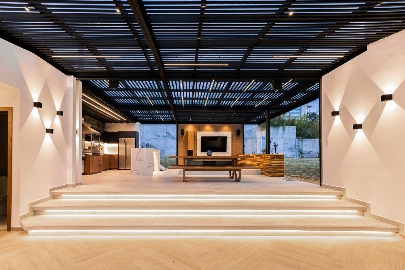Open-plan living space with a pergola ceiling and warm lighting